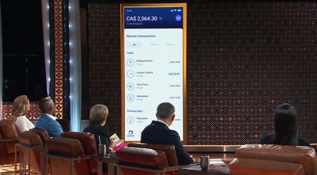 Five individuals sit facing a large screen featuring the Hutsy banking app