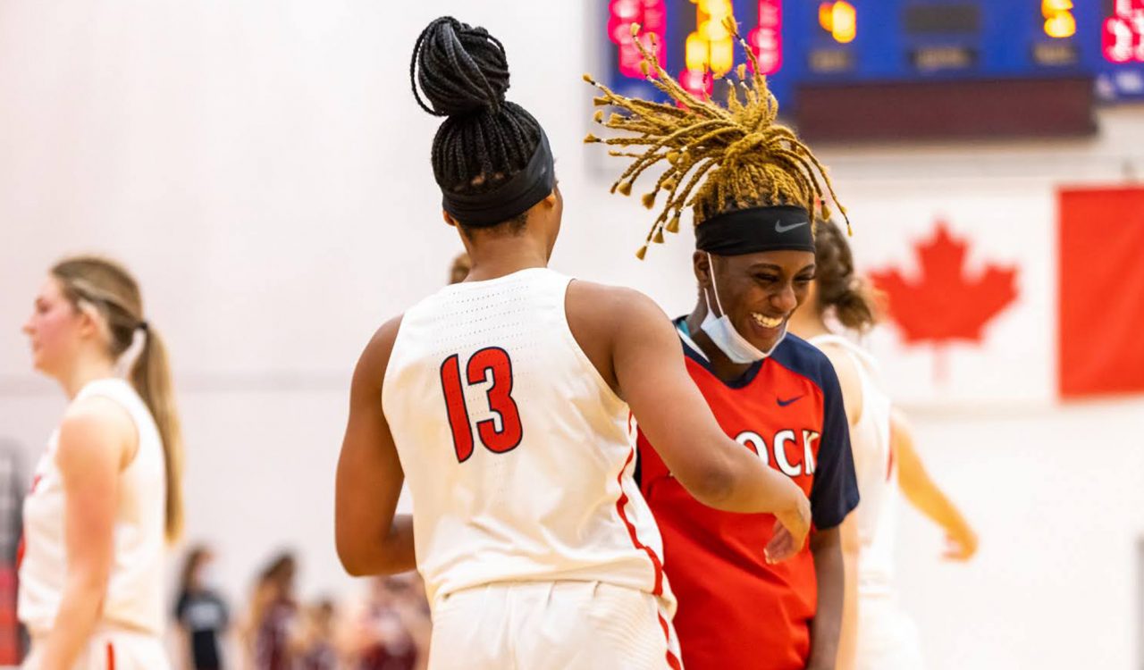 Two female basketball players having a friendly exchange on the court.