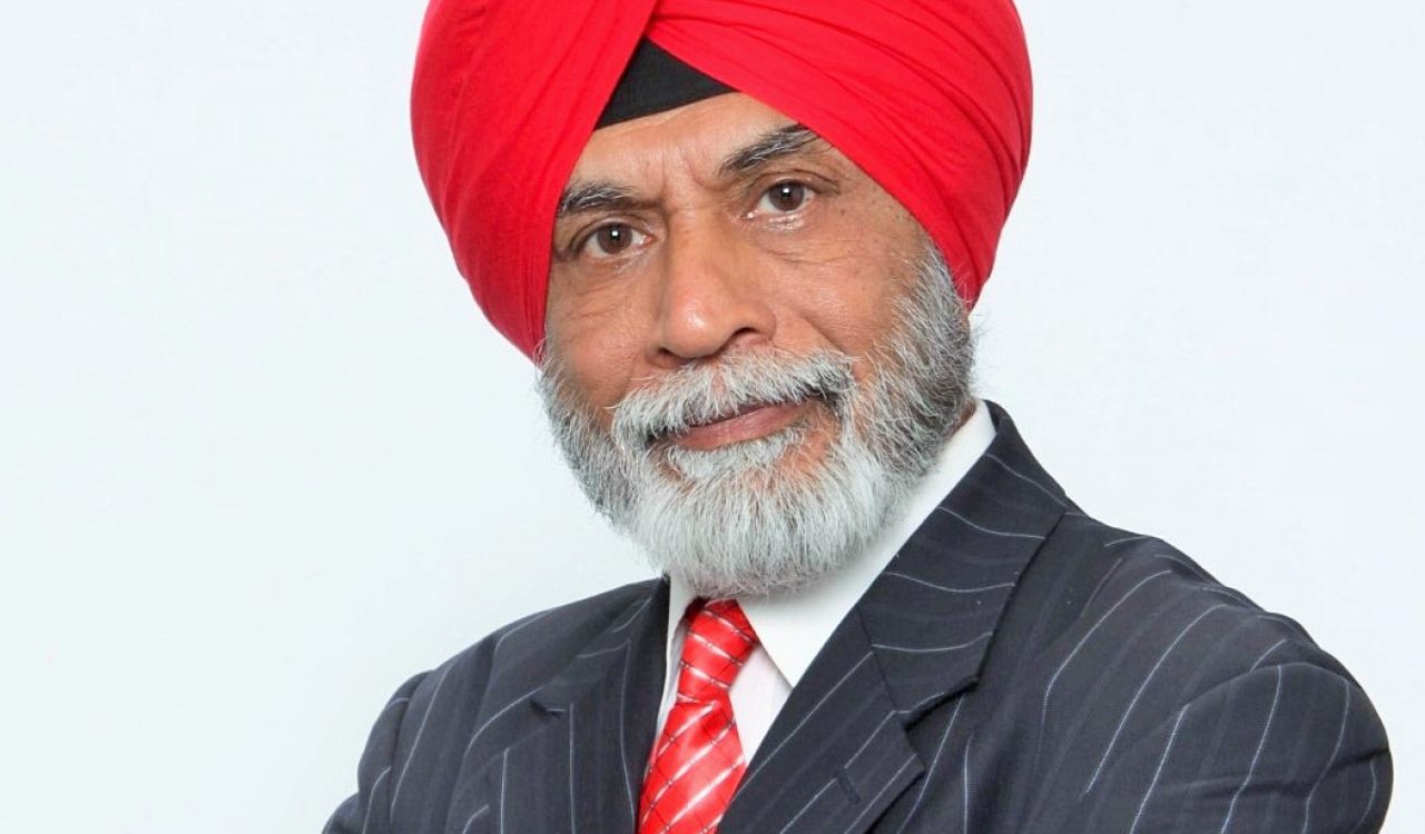 A head-and-shoulders photo of a man in a suit with a red tie and turban.