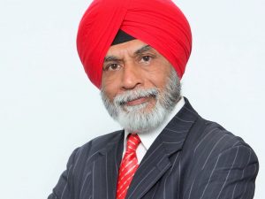 A head-and-shoulders photo of a man in a suit with a red tie and turban.