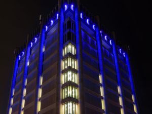 A large 13-storey tower is seen at night with blue lights illuminating the top portion.