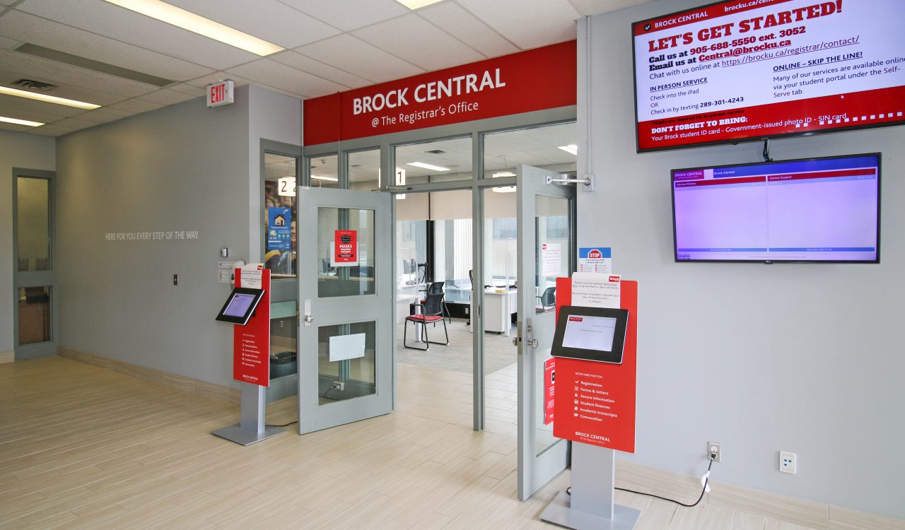 The main entrance to the Brock Central @ The Registrar’s Office location, with silver lettering on a red sign above an open door.