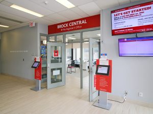 The main entrance to the Brock Central @ The Registrar’s Office location, with silver lettering on a red sign above an open door.