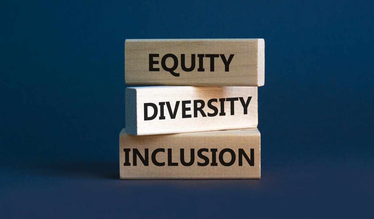 Three stacked wooden blocks read “Equity/Diversity/Inclusion” against a blue background