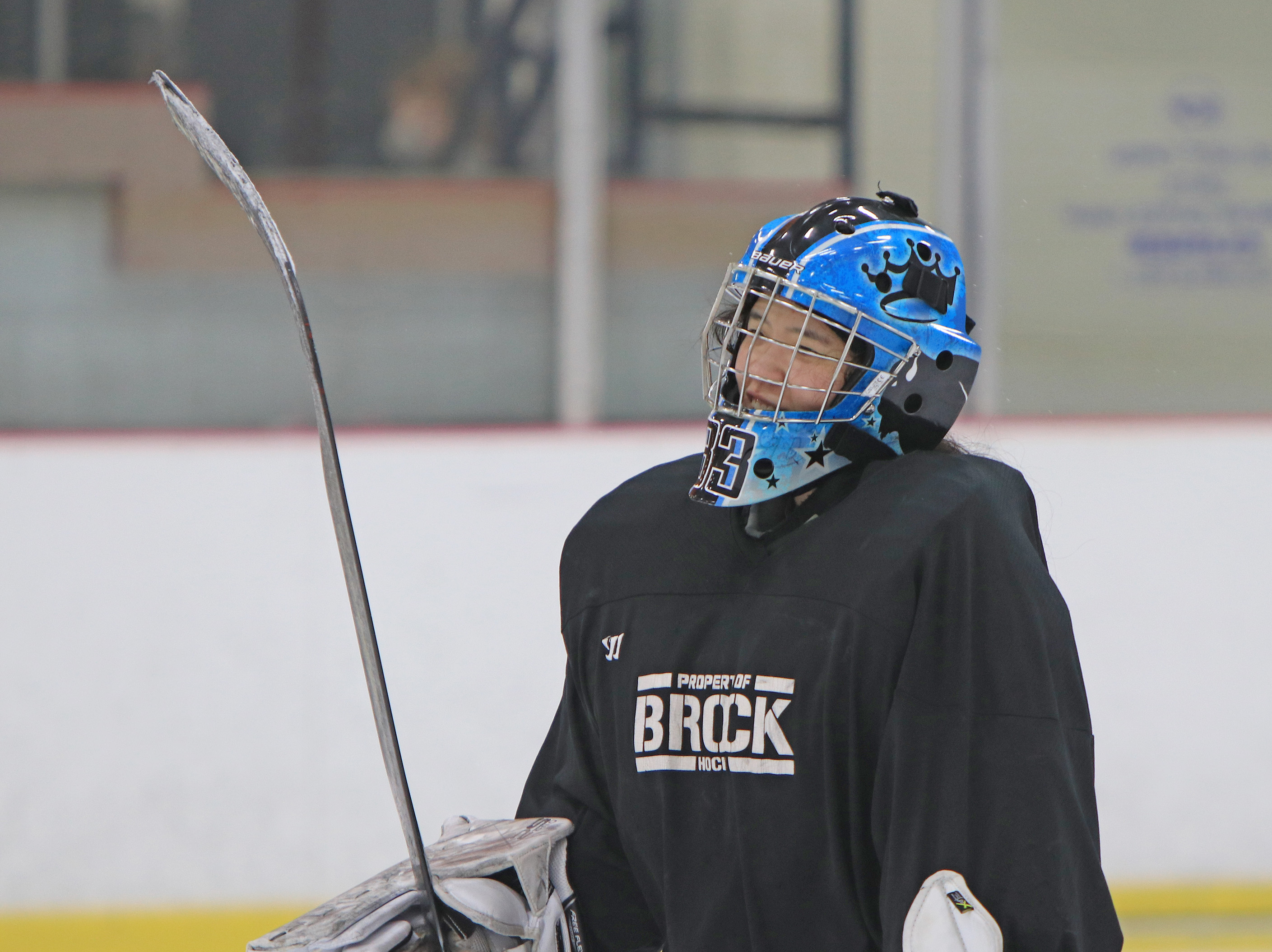 A woman in hockey equipment smiles.