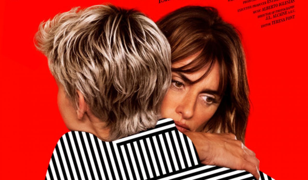 Two women embrace against a bright red background in the poster for the film Parallel Mothers.