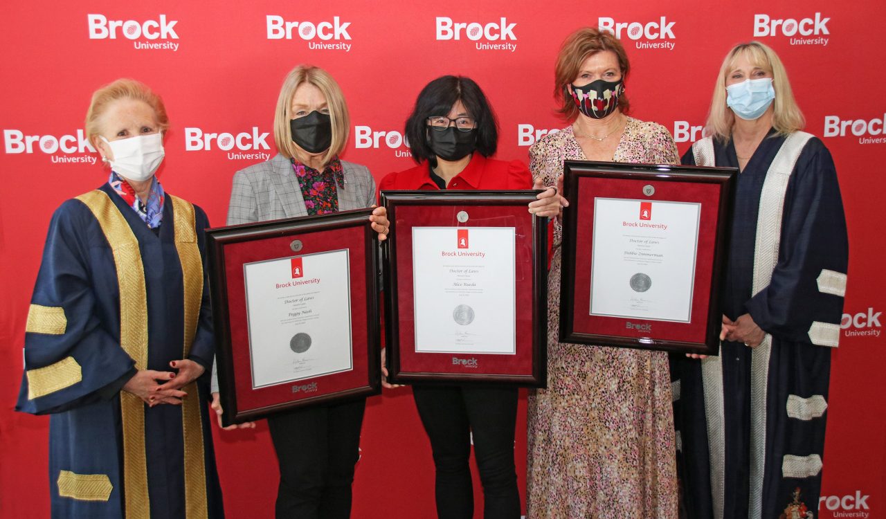 Five women are pictured with three holding honorary degrees.