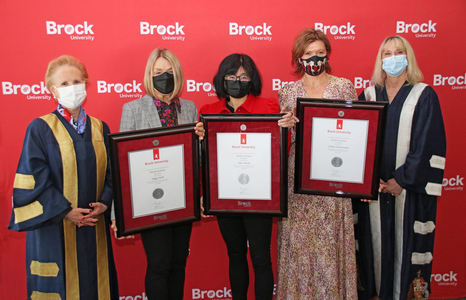Five women are pictured with three holding honorary degrees.