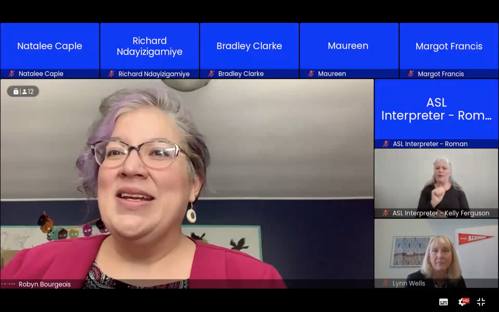 A screenshot of participants in an online meeting. A large box in the centre shows a woman speaking. Several blue boxes around the woman represent other people who will be presenting at the meeting. Their video cameras are off so all that is seen is their name written in text. Two of the small boxes show the faces of two other women.