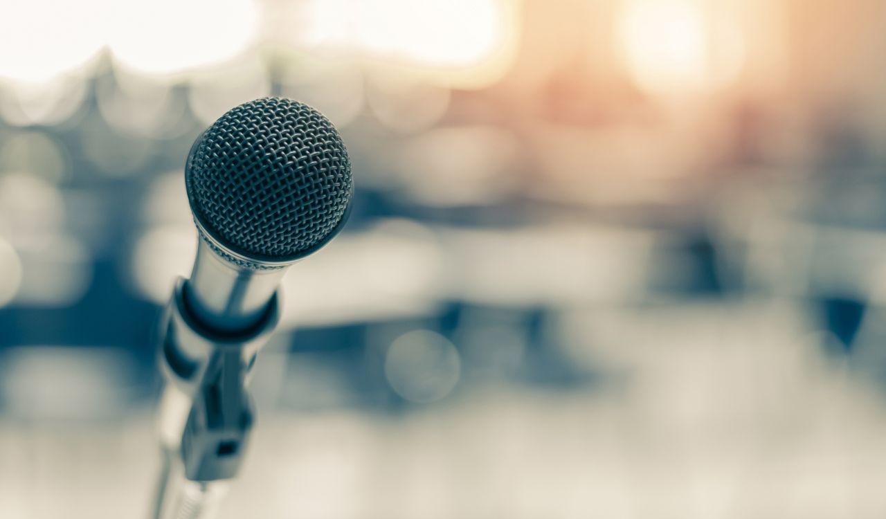A microphone in front of a blurred background of an auditorium.