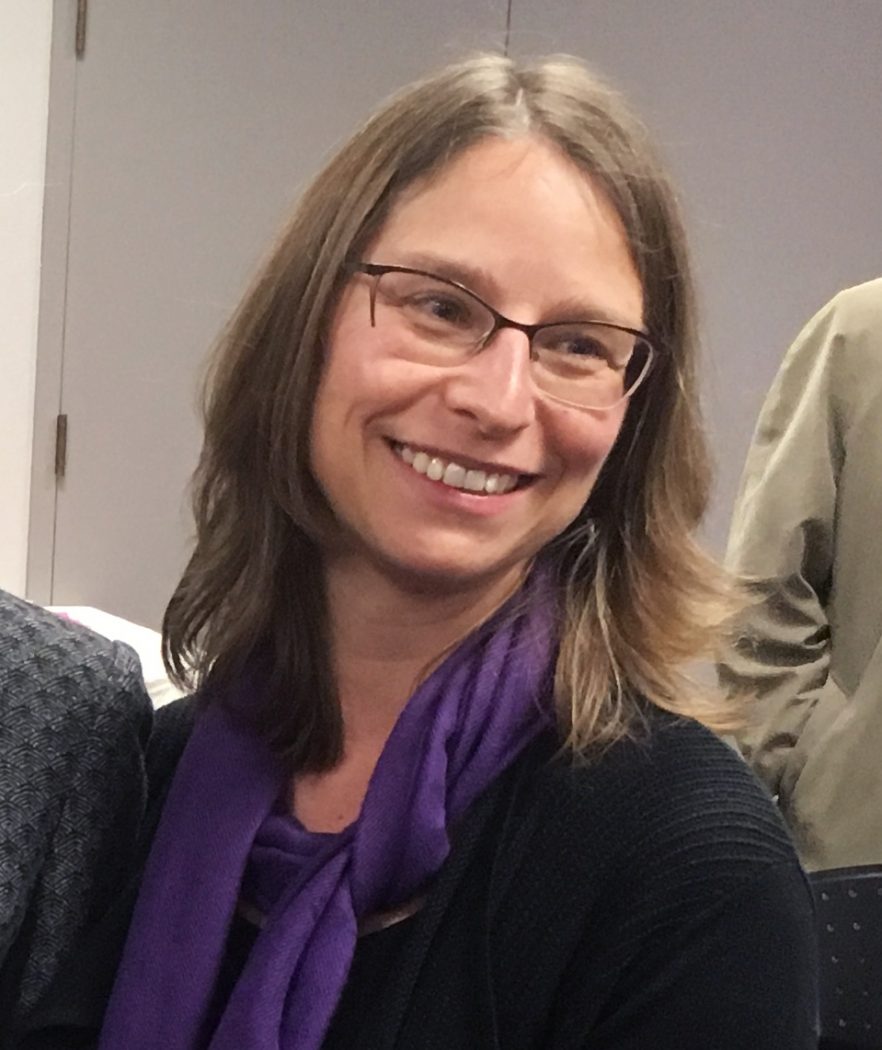 Headshot of a woman with glasses and a purple scarf.