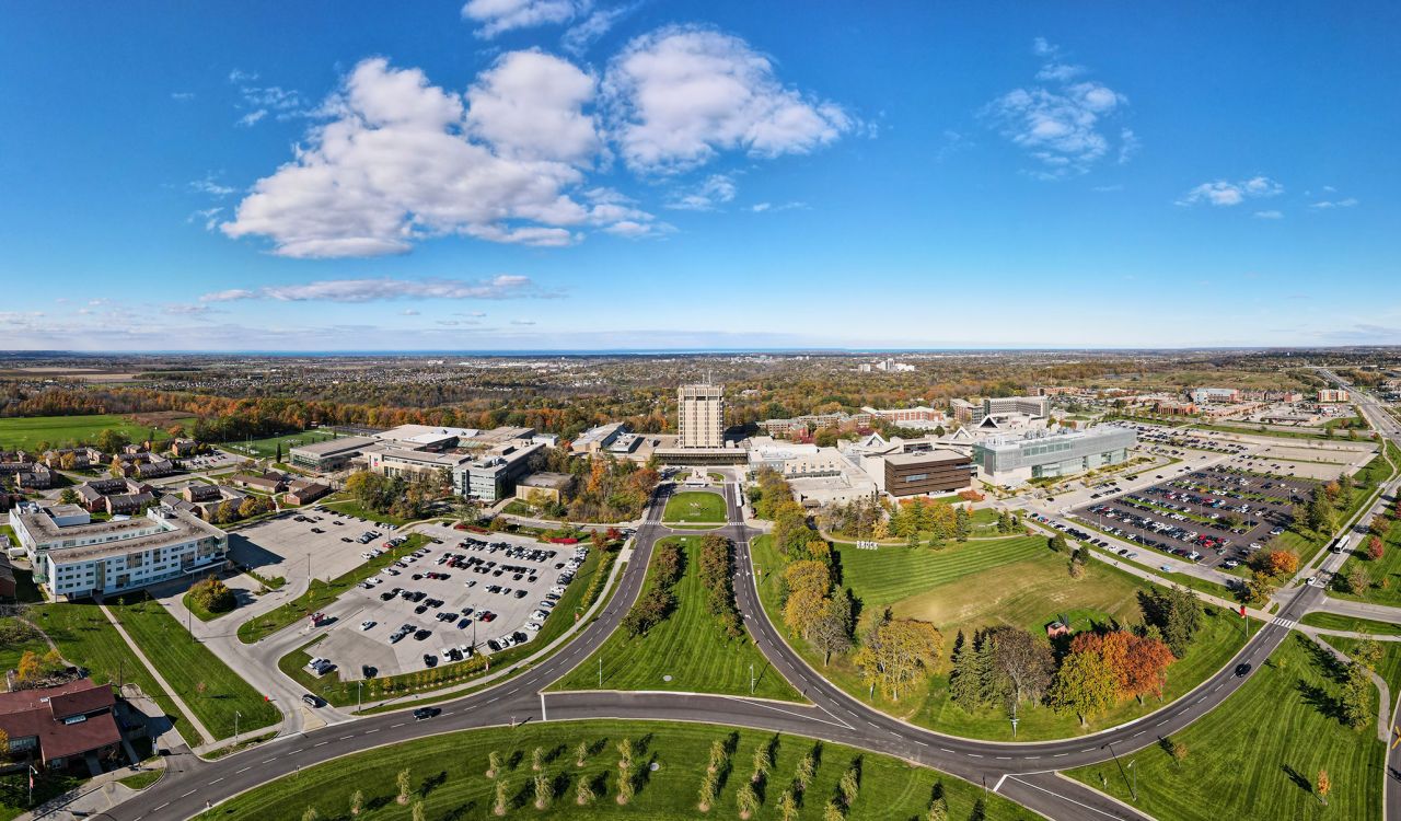 a wide angle view of Brock University's campus with greenery, buildings and blue skies.