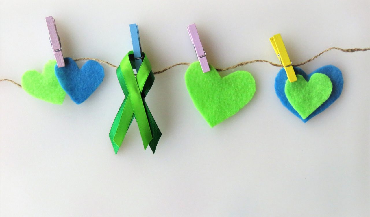 Green and blue felt hearts and green awareness ribbons are attached to a line of twine with colourful clothes pins.