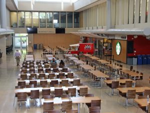 An empty dining hall with rows of chairs and tables.