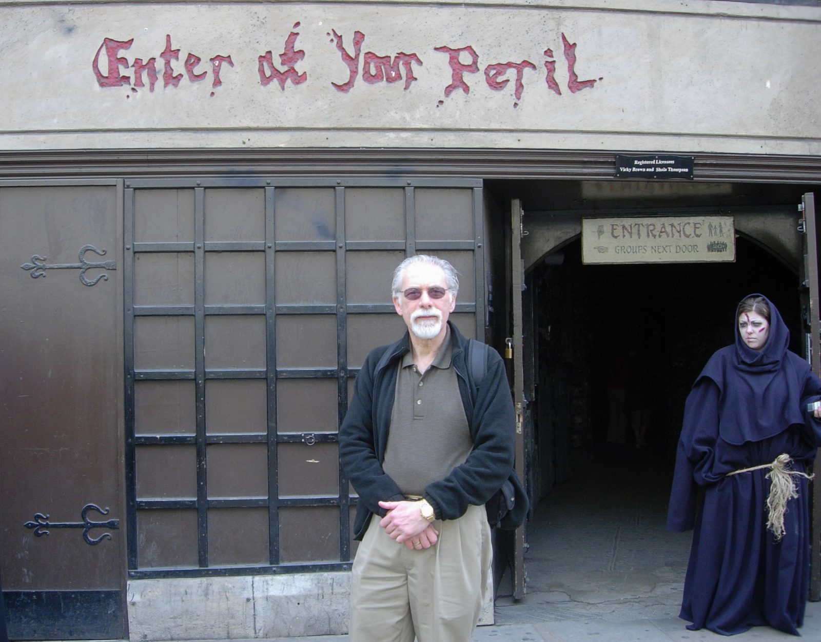 Professor Emeritus Barry Grant stands in front of a commercial haunted house.