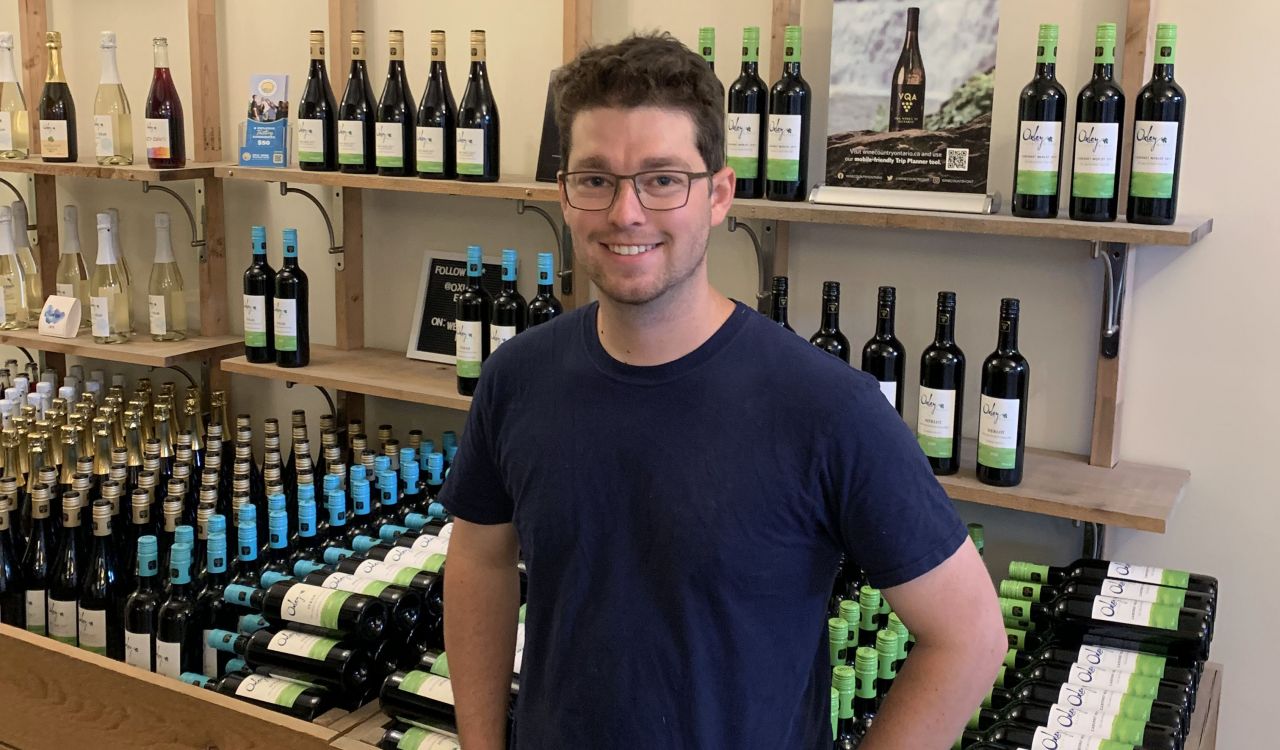 A man poses in front of a wall of VQA wines.