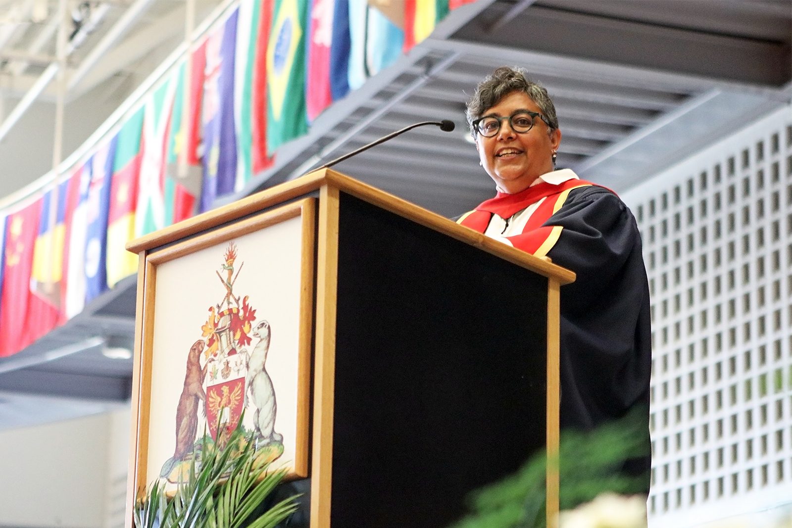 A woman in a graduation gown stands at a podium.