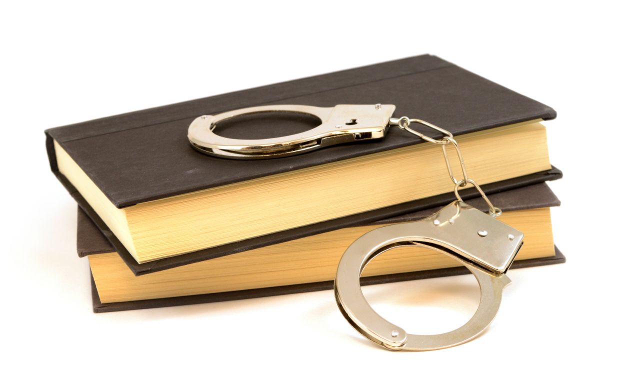 An isolated set of books and handcuffs for the educational study of law and order.