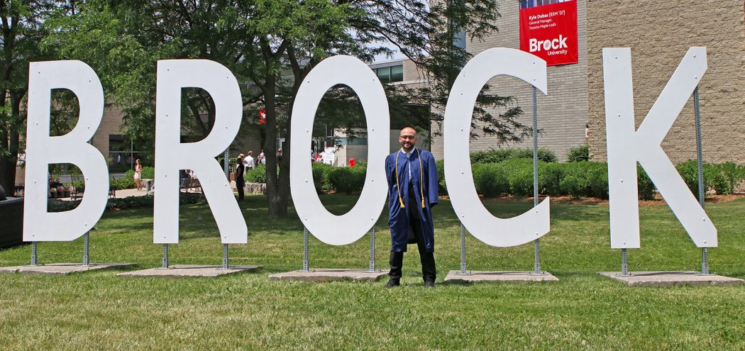 A man stands amongst large white letters that read 'BROCK.'