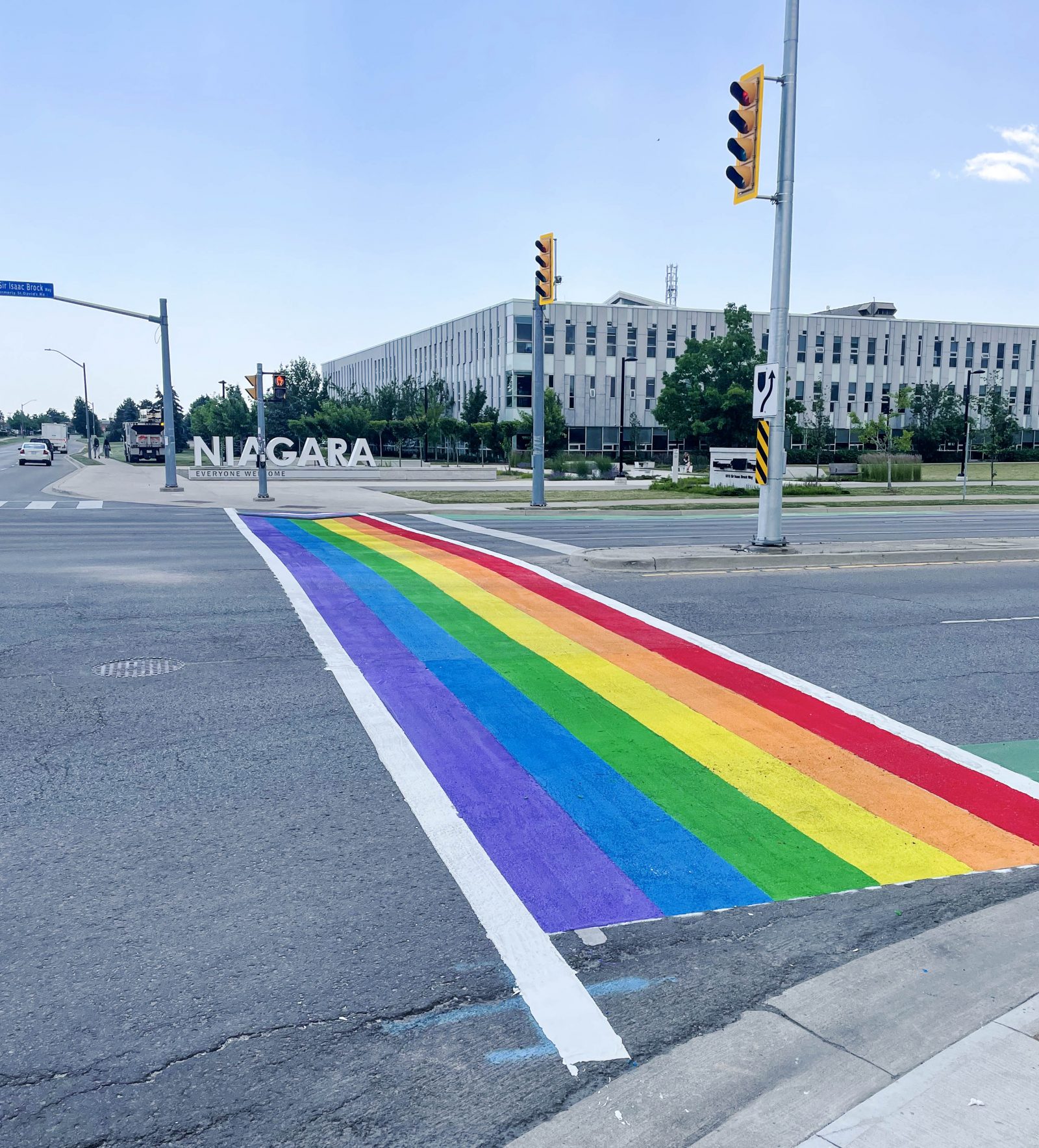 A crosswalk painted with the colours of the rainbow appears in the foreground, leading to a sign that says 'NIAGARA.'