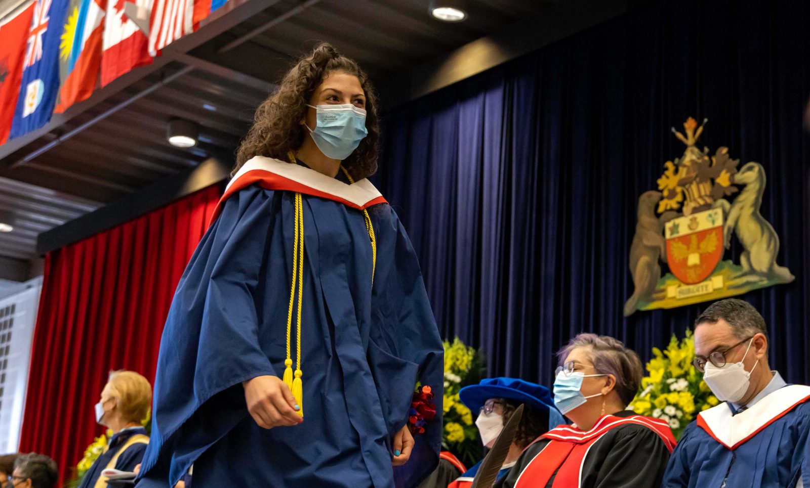 A woman walks across a stage wearing a graduationgown.