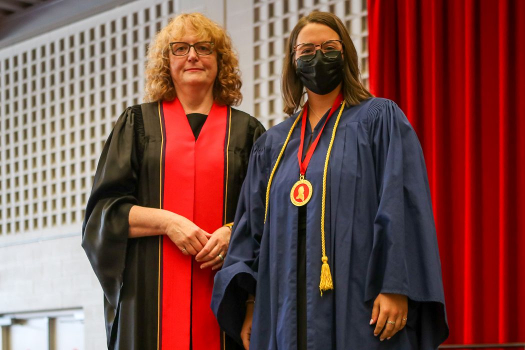 Two women in Convocation gowns stand together.