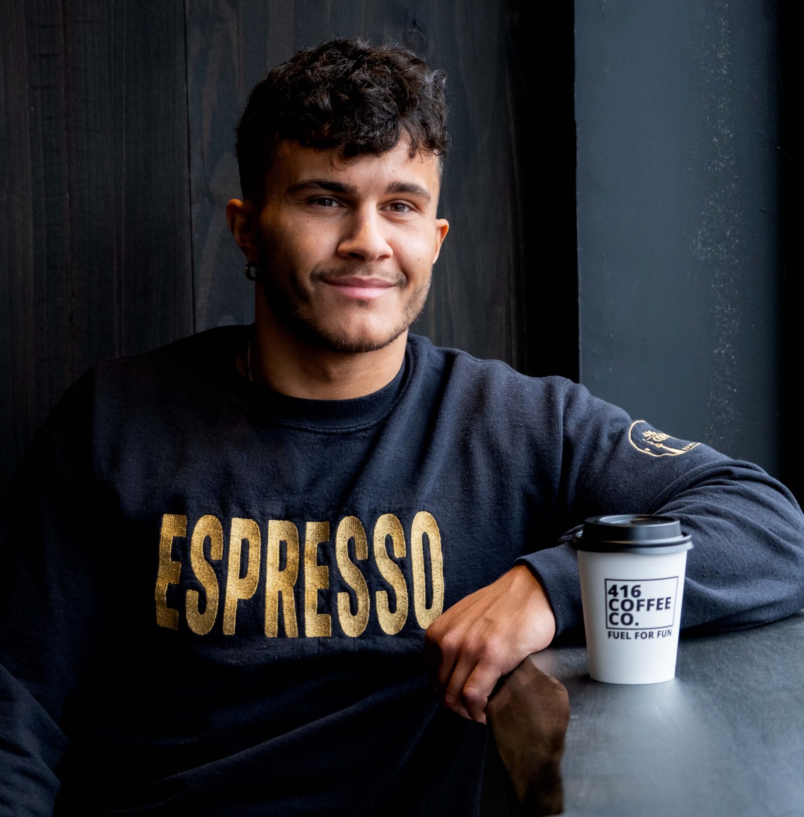 Profile picture of Chris Battagli wearing a sweater that says ‘ESPRESSO’ in gold block letters.