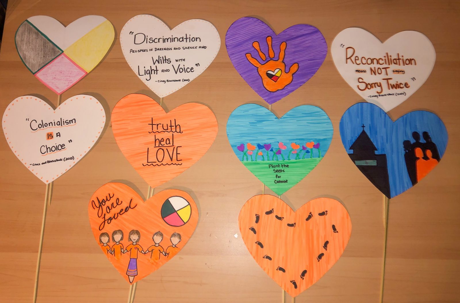 Paper hearts attached to small sticks feature quotes and images about reconciliation and decolonization.