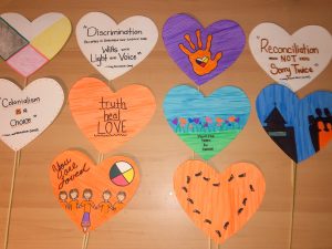 Paper hearts attached to small sticks feature quotes and images about reconciliation and decolonization.