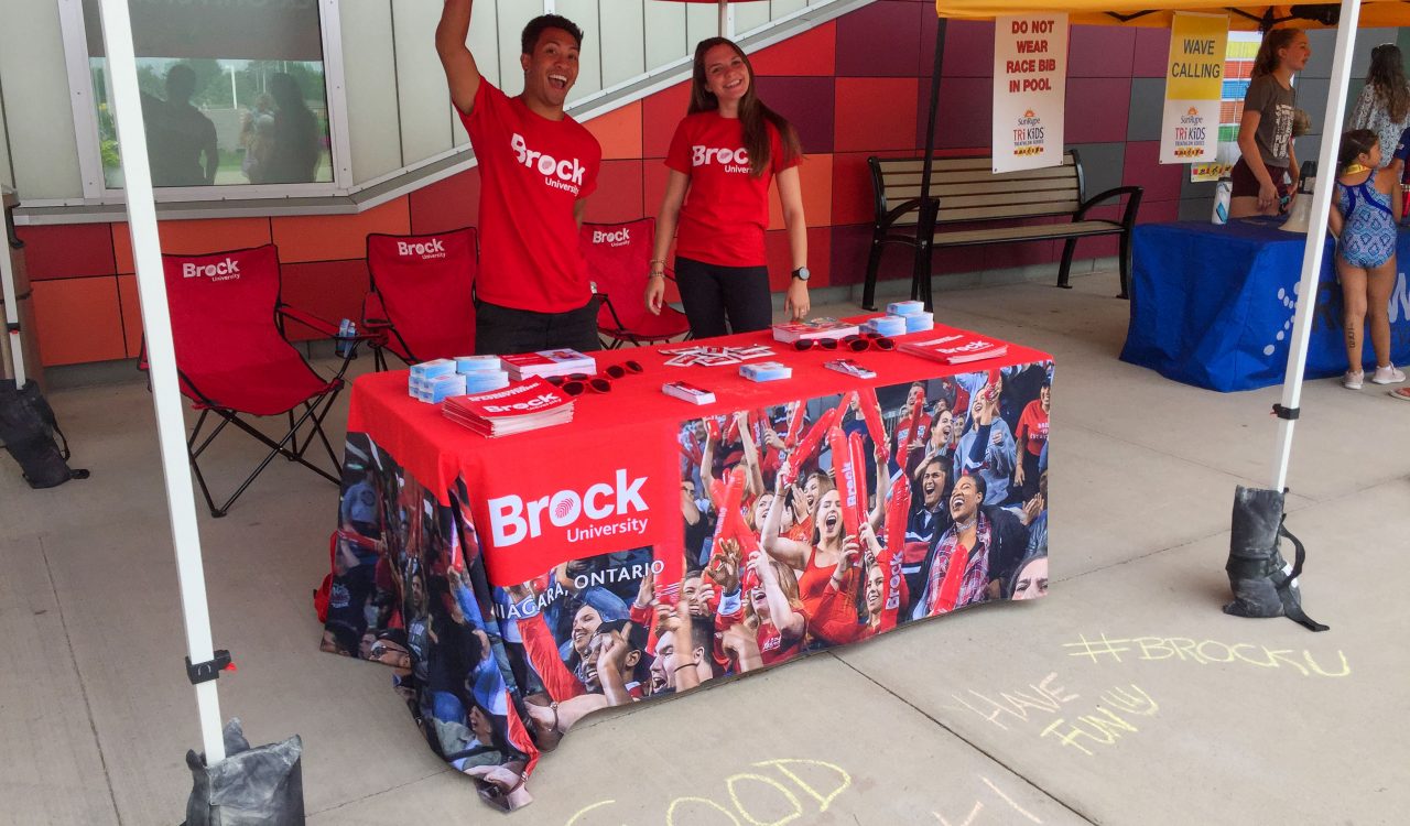 Two students stand under a promotion tent