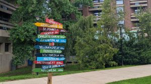 A multi-coloured sign featuring the names of Canadian cities with their distance from St. Catharines, Ont.