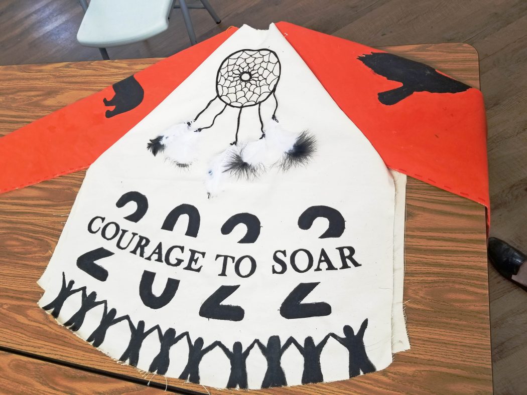A painted jersey with orange arms and a white body that reads '2022 Courage to Soar.'
