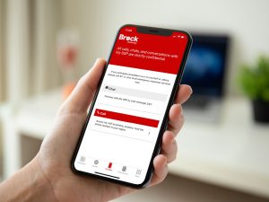 A hand holds a phone that displays the Brock University My SSP mobile app in red and white.