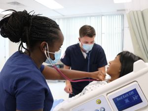 Two Brock Nursing students practise their skills by working with a high-fidelity simulator that looks like an adult patient.