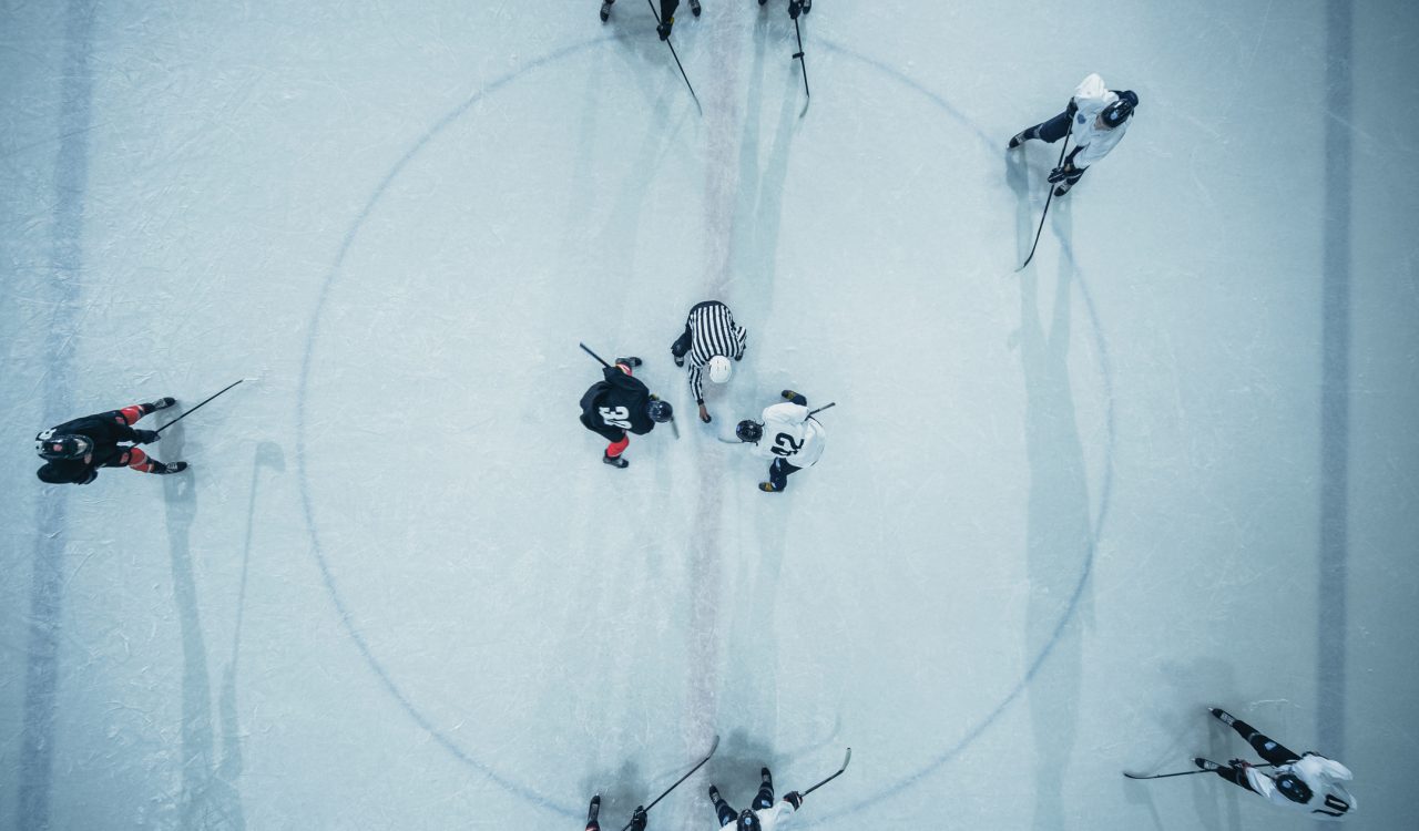 An aerial view of hockey players facing off at centre ice.