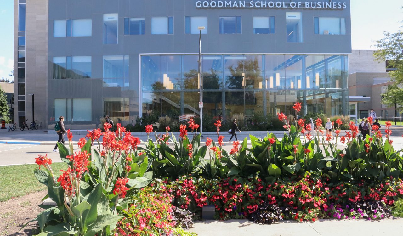 A building with large glass windows in the background and flowers in the foreground.