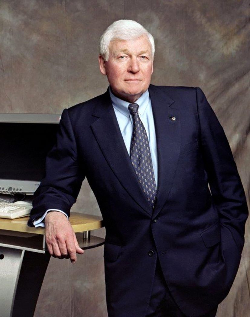A portrait of L.R. Wilson, who is wearing a suit and leaning on a computer table.