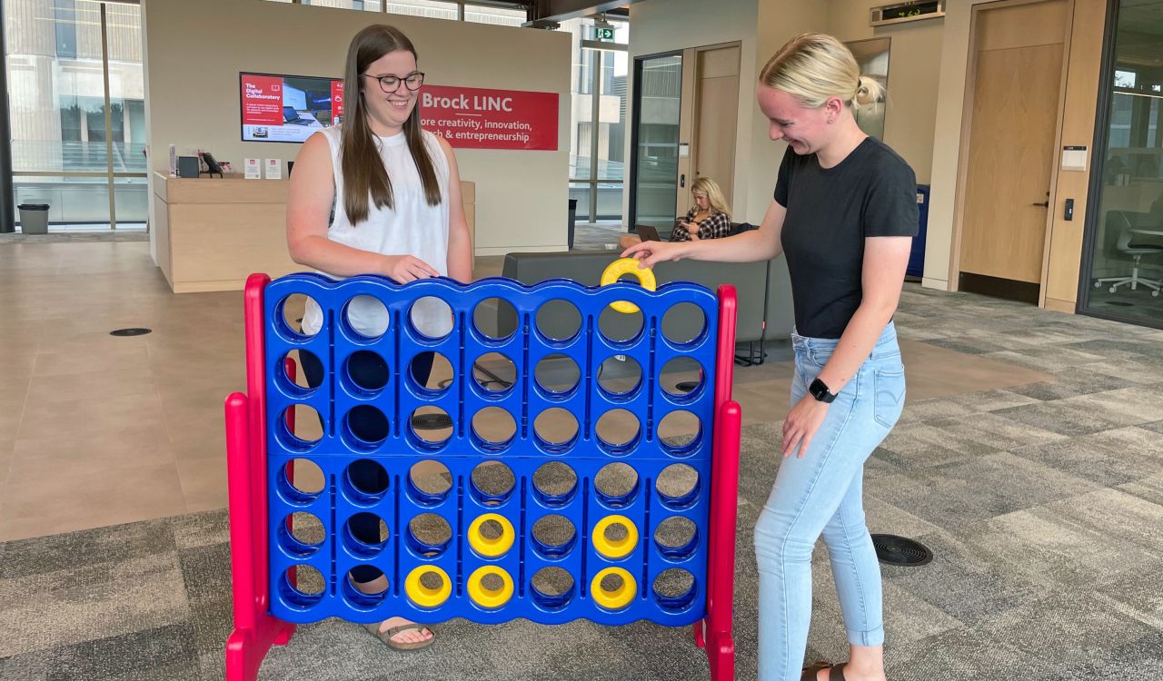 Two girls play giant Connect 4.