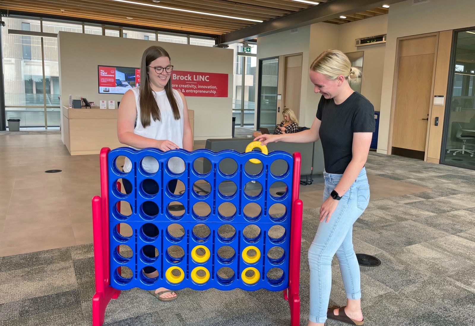 Two girls play giant Connect 4.