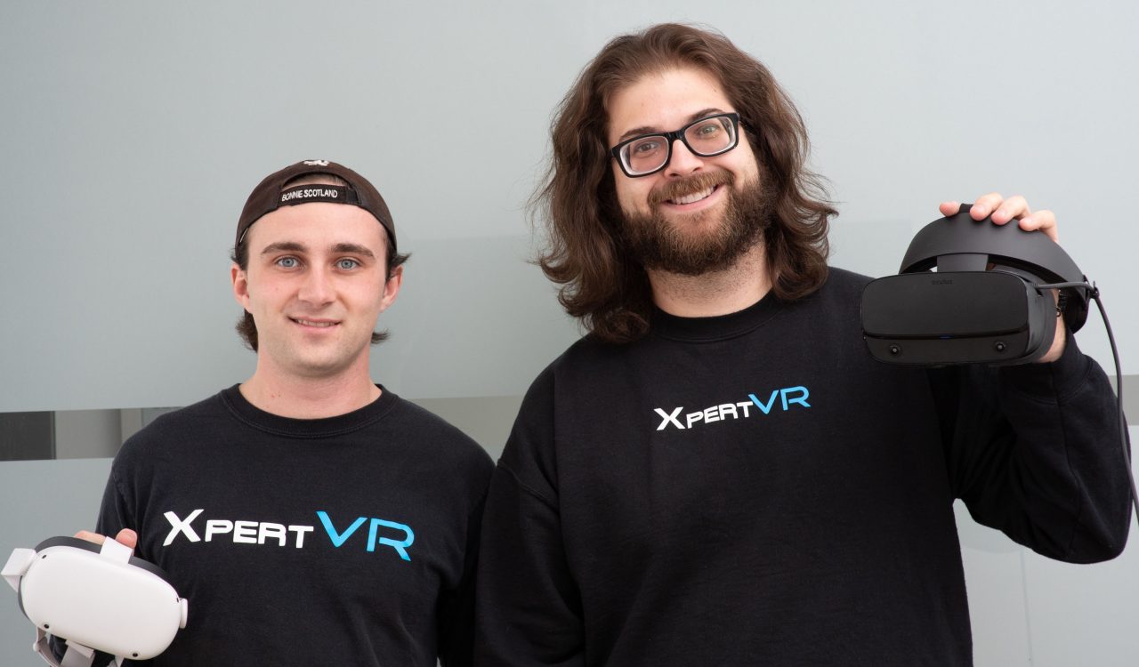 [4:09 p.m.] Maryanne St. Denis Two men in black sweaters stand with virtual reality headsets.
