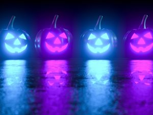 Four jack-o-lanterns, two lit in blue and two in purple, on a dark background.