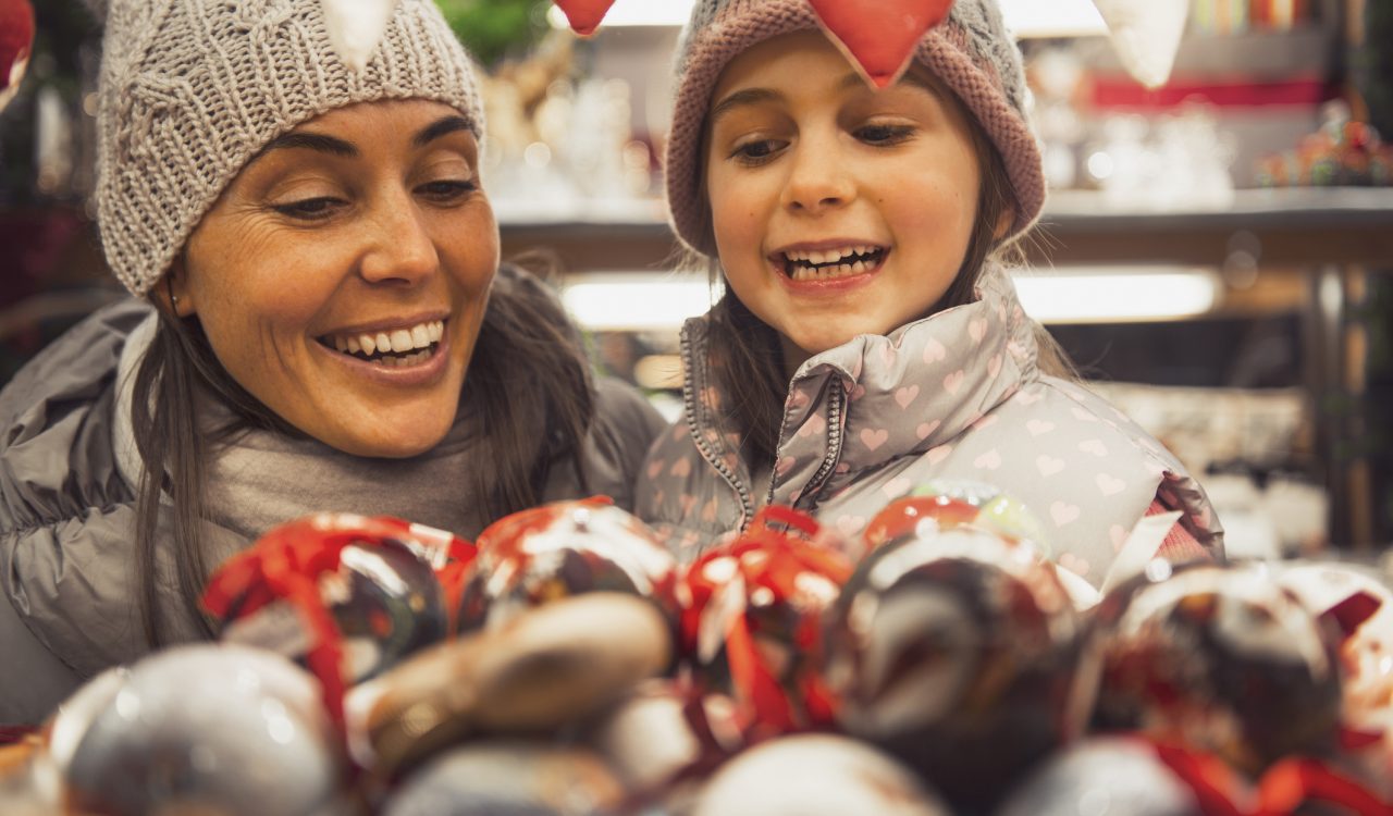 A mother and daughter selecting a decoration at a holiday market.