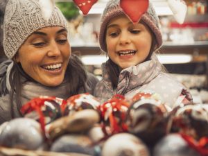 A mother and daughter selecting a decoration at a holiday market.