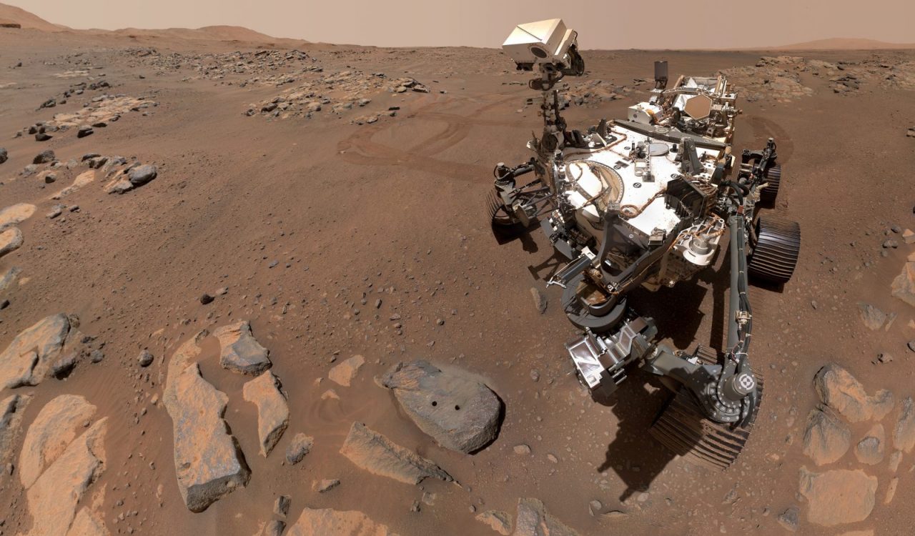 A wheeled space rover sits on the rocky red surface of Mars.