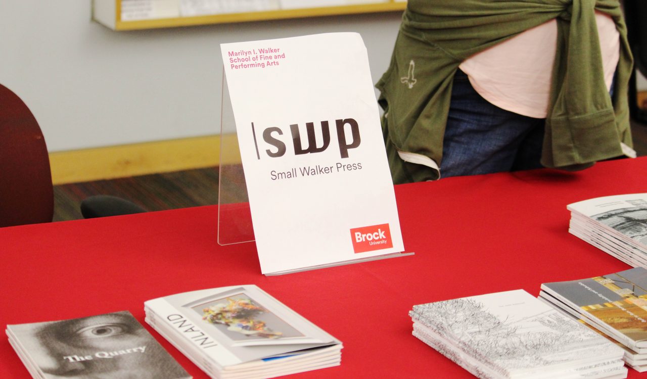 A tabletop banner reads “SWP Small Walker Press” set atop a red table cloth with a collection of books and publications.