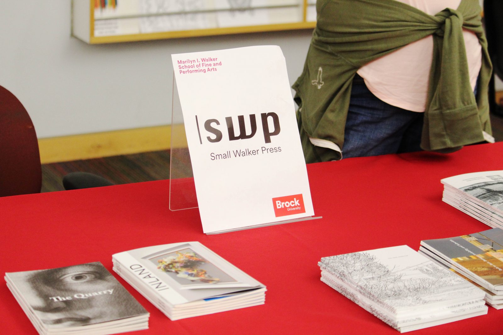A tabletop banner reads “SWP Small Walker Press” set atop a red table cloth with a collection of books and publications.