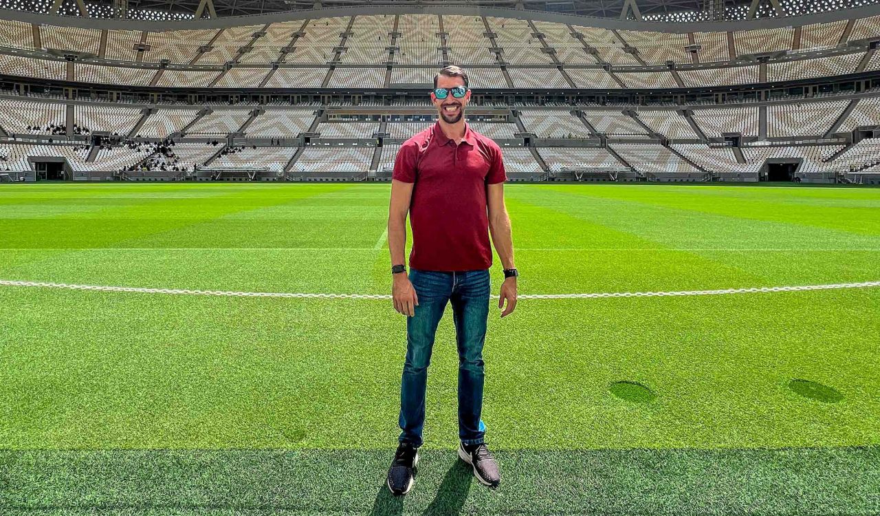 A man stands in a soccer stadium under the sun.