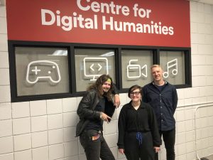 Three people stand in front of Brock’s Centre for Digital Humanities sign.