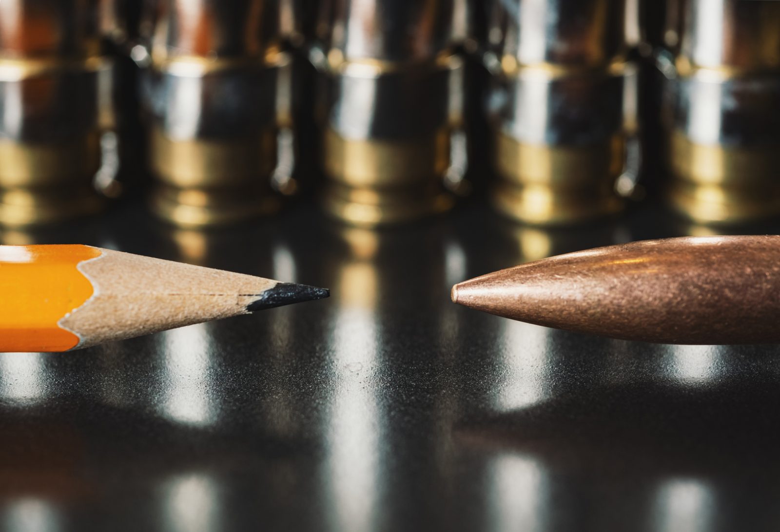 A pencil tip is pointed inwards on the left and a bullet tip pointed inwards on the right.