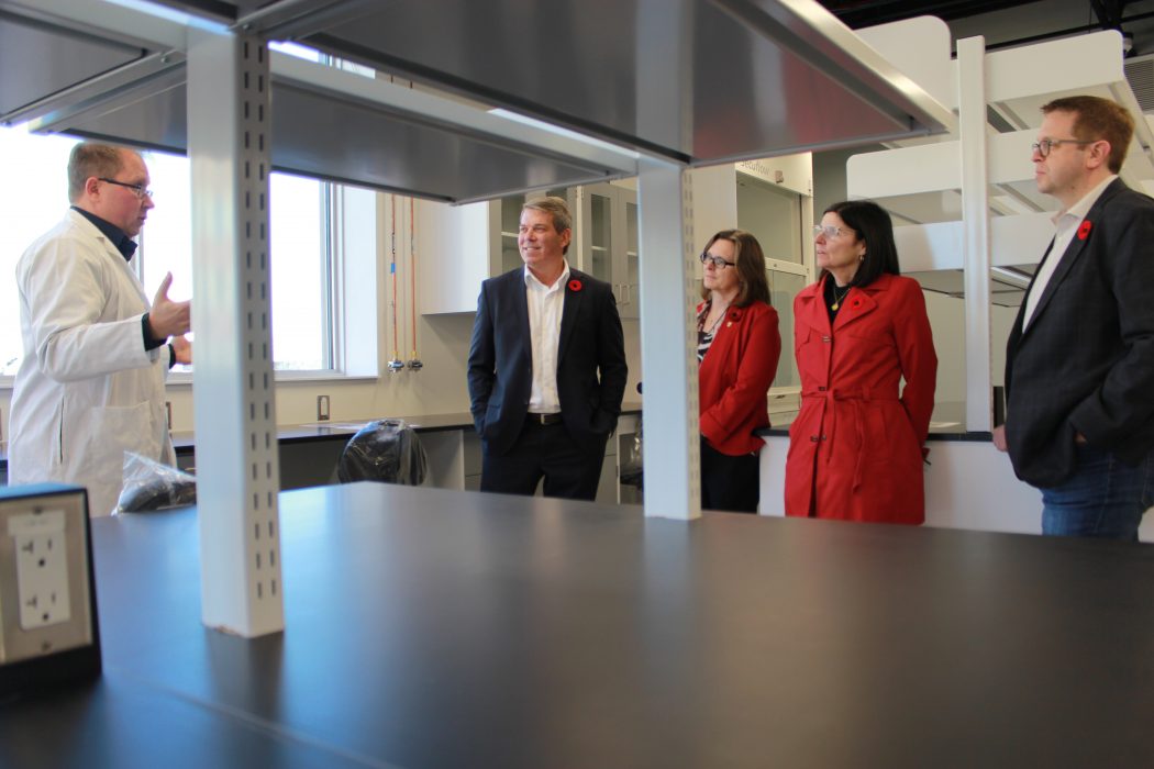 Five people stand together in a room, one leading a discussion.